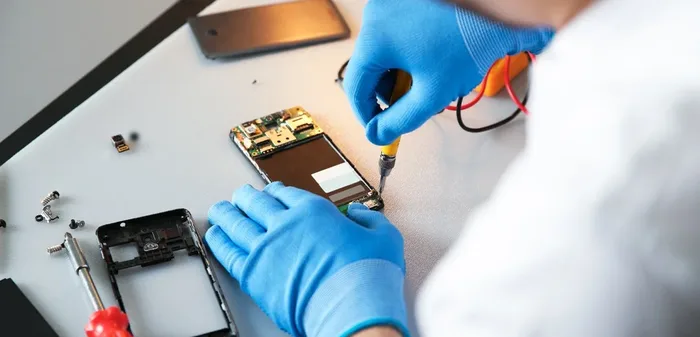 Technician timing a phone repair on a workbench